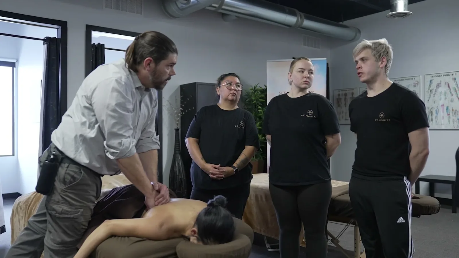 An instructor demonstrating massage technique to a group of students