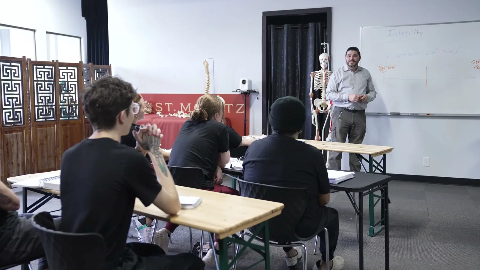 A St. Moritz instructor teaching a massage therapy class at the whiteboard
